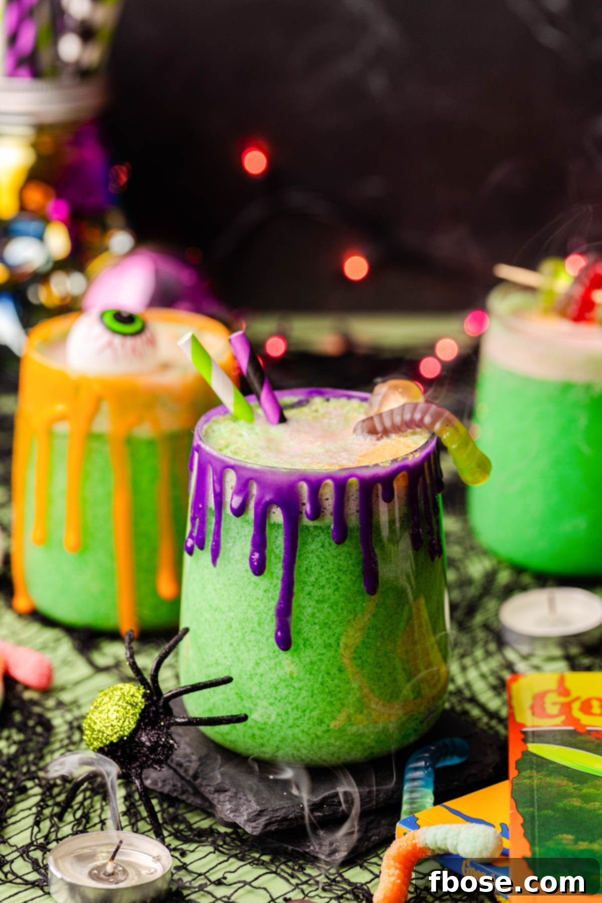 Close up photo of glasses of vibrant green Halloween punch on a table adorned with spooky decorations, creating a festive party atmosphere.