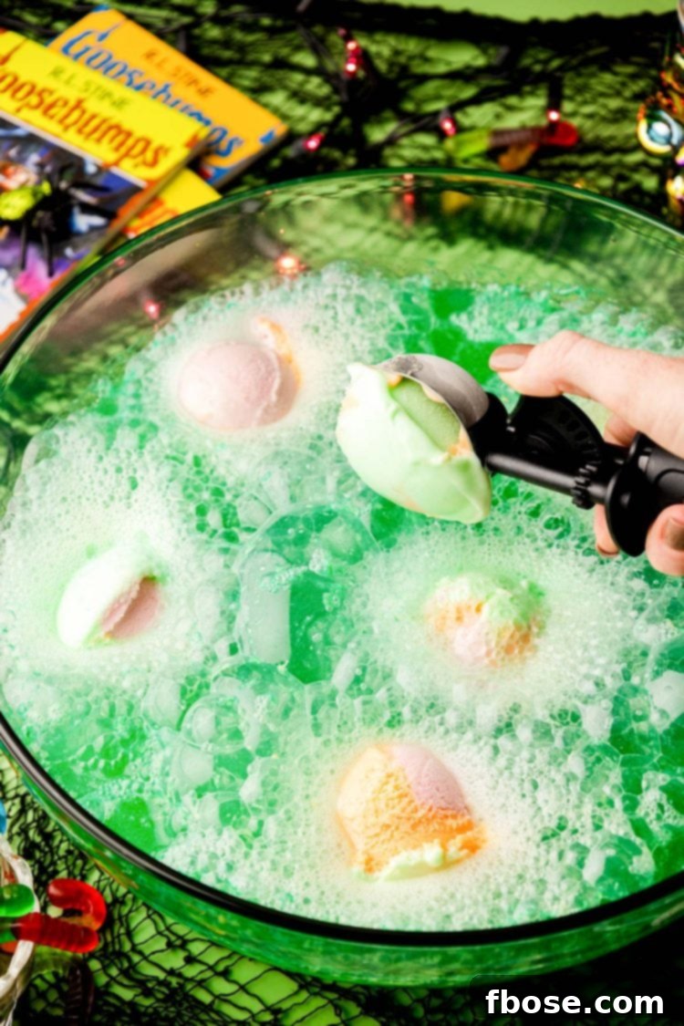 A close up of green Halloween punch in a bowl with sherbet melting.