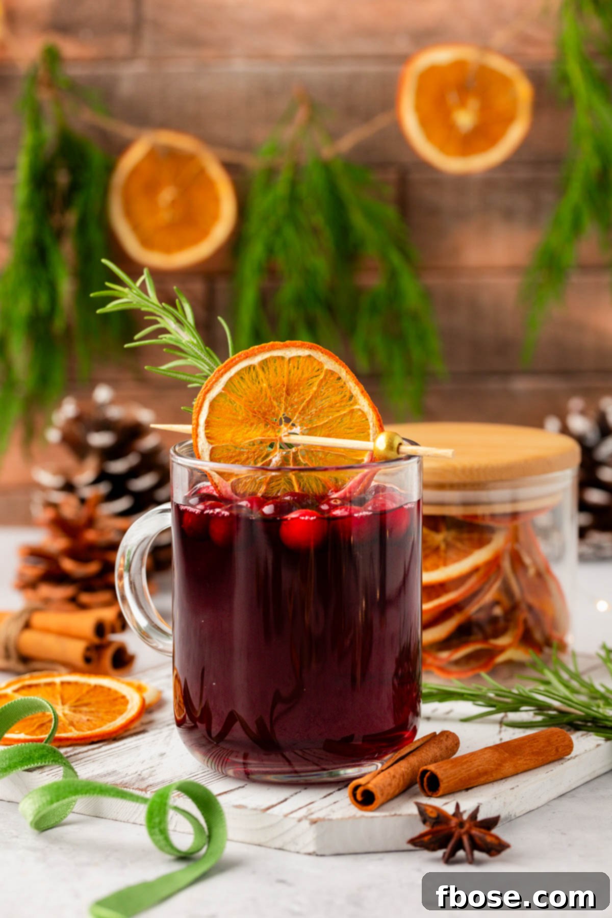 Oven-Dried Orange Slices 11 A cozy mug of mulled wine, garnished with a dried orange slice and a cinnamon stick, surrounded by festive decor.