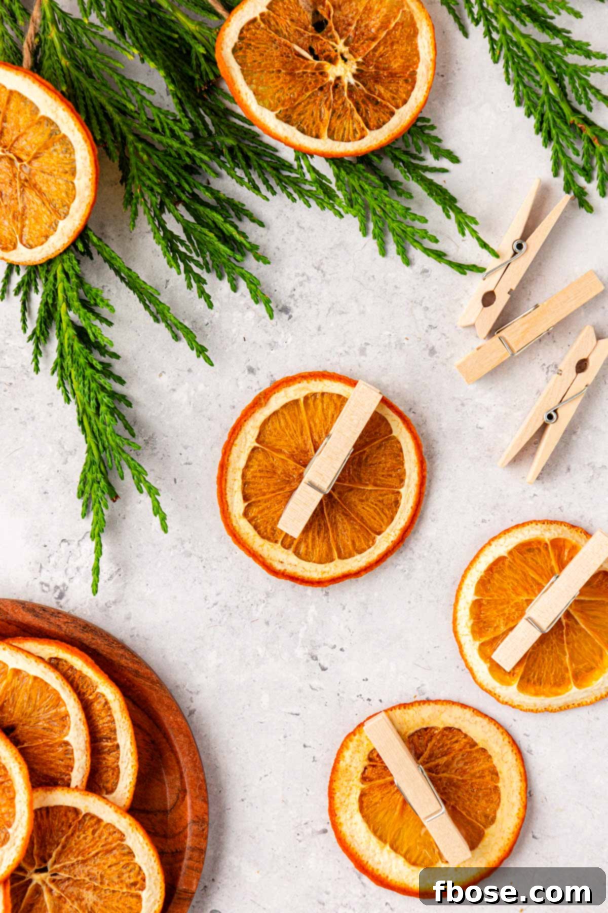 Oven-Dried Orange Slices 12 A close-up shot of mini clothespins being attached to dried orange slices with hot glue, for DIY ornaments.