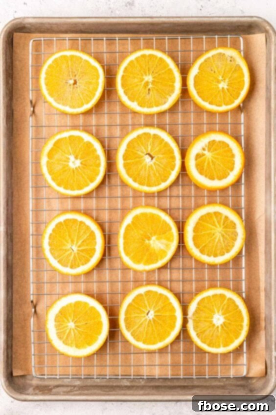 Orange slices arranges on a wire rack on a baking sheet to dry them out.