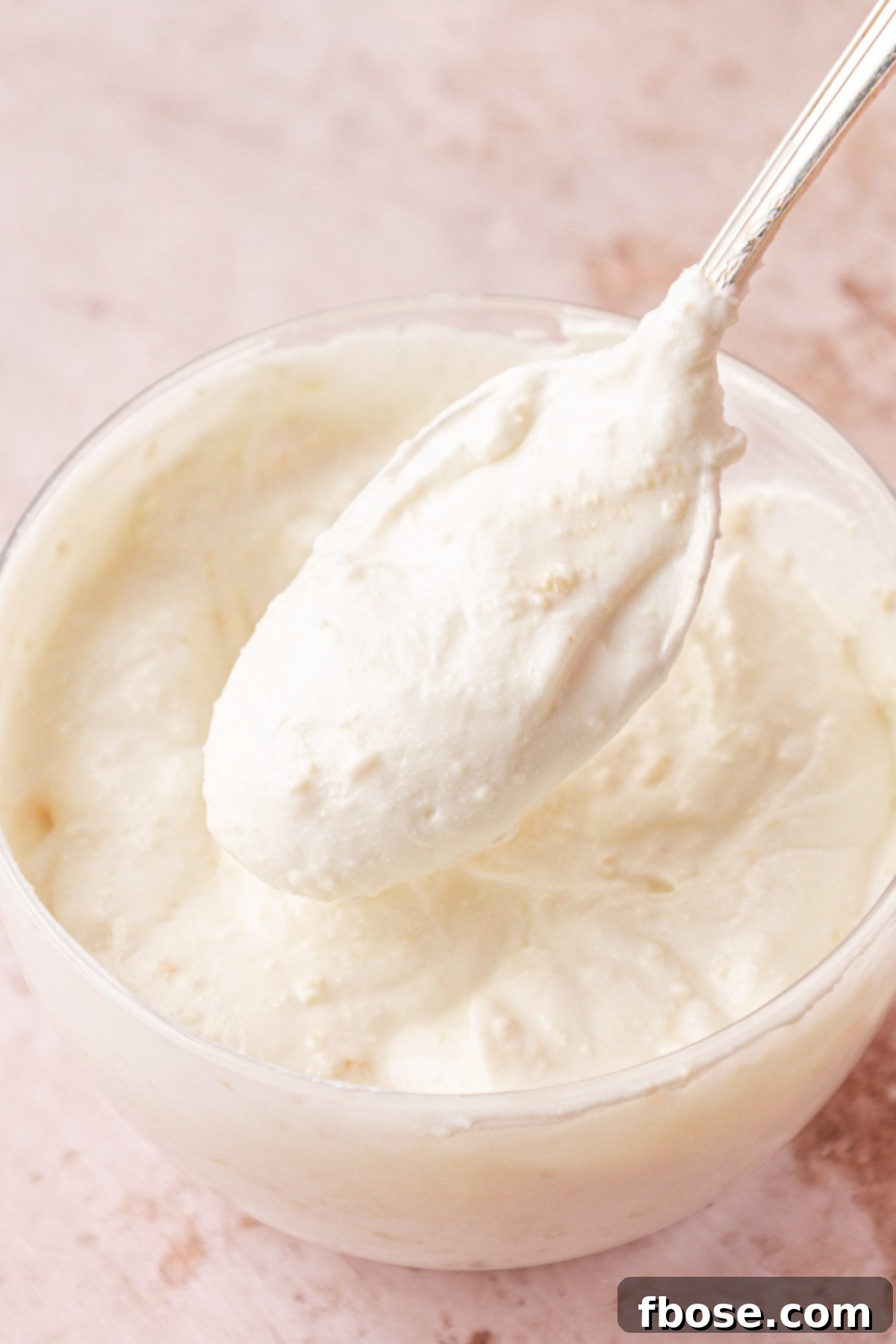 Lemon garlic yogurt sauce being scooped from a bowl with a spoon.