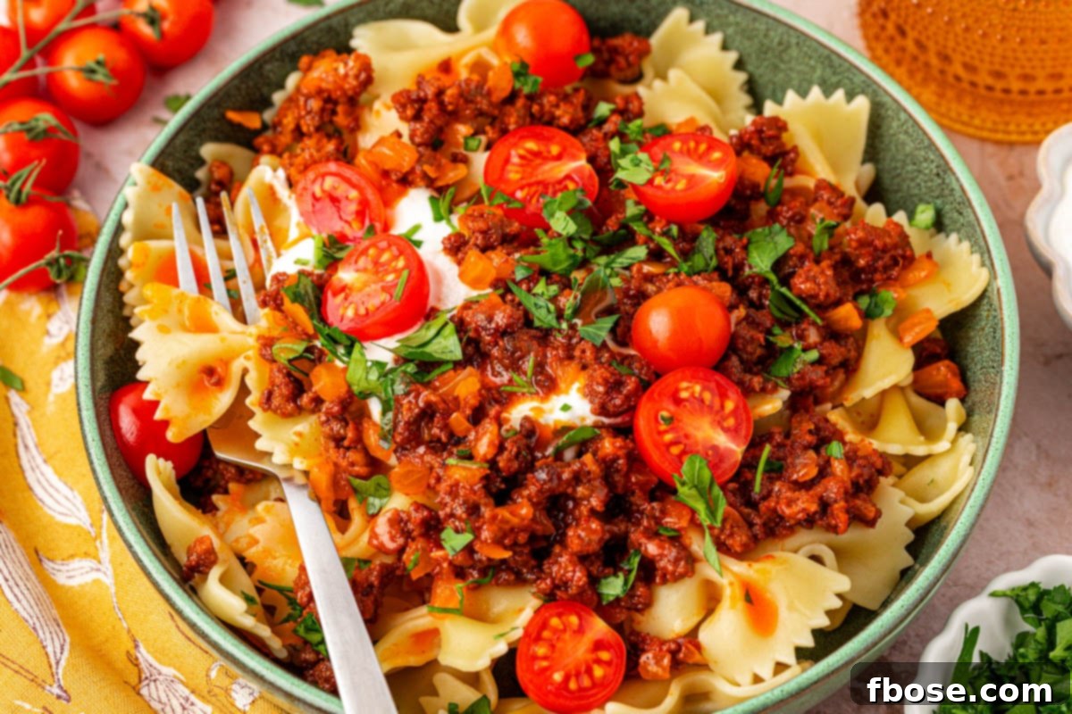 A teal bowl filled with Turkish pasta, with a fork resting on the side, inviting a delicious bite.