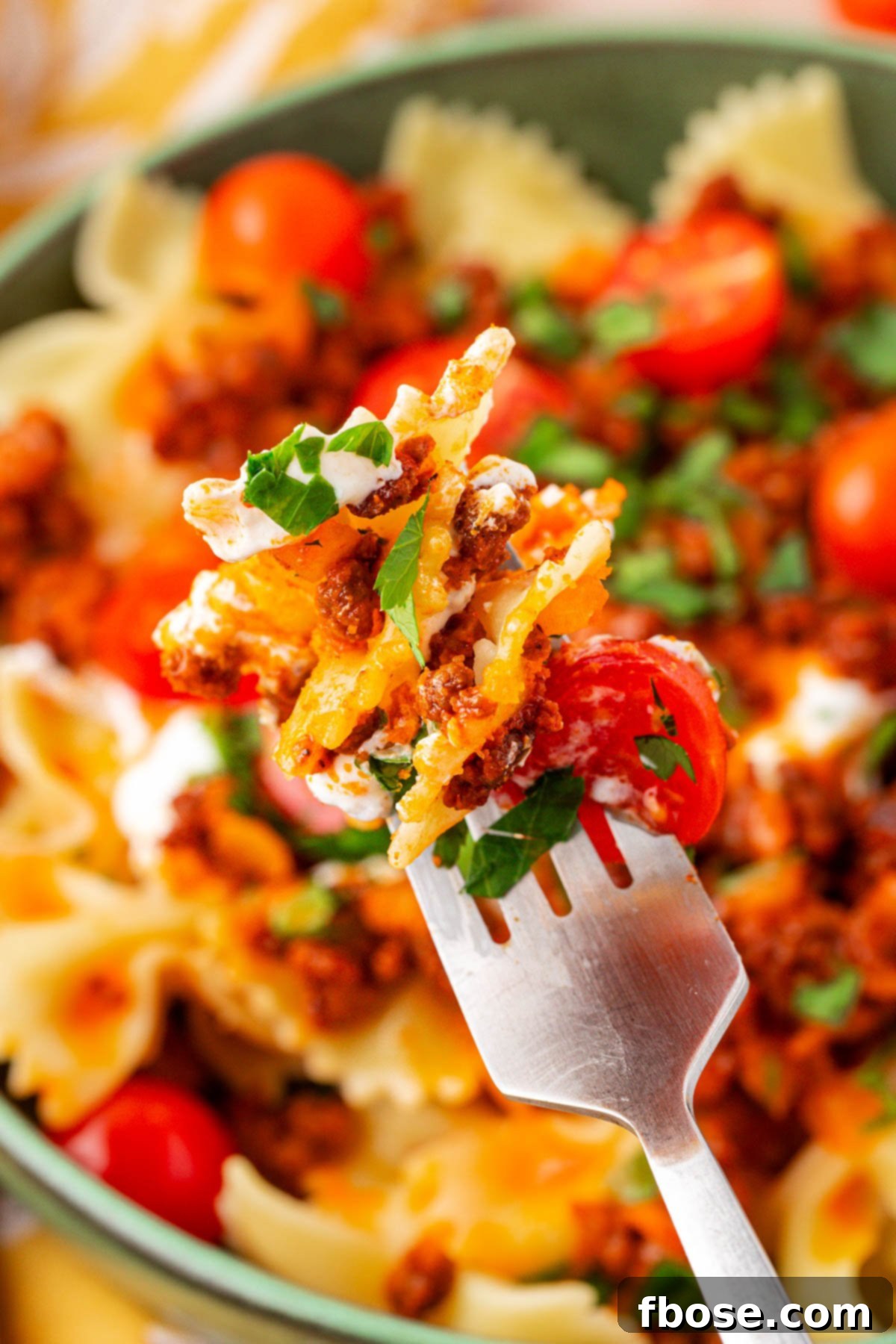 A forkful of Turkish pasta, showing the layers of pasta, beef, and yogurt sauce.