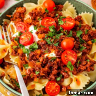 A teal bowl filled with Turkish pasta with a fork sitting on the side of the bowl.