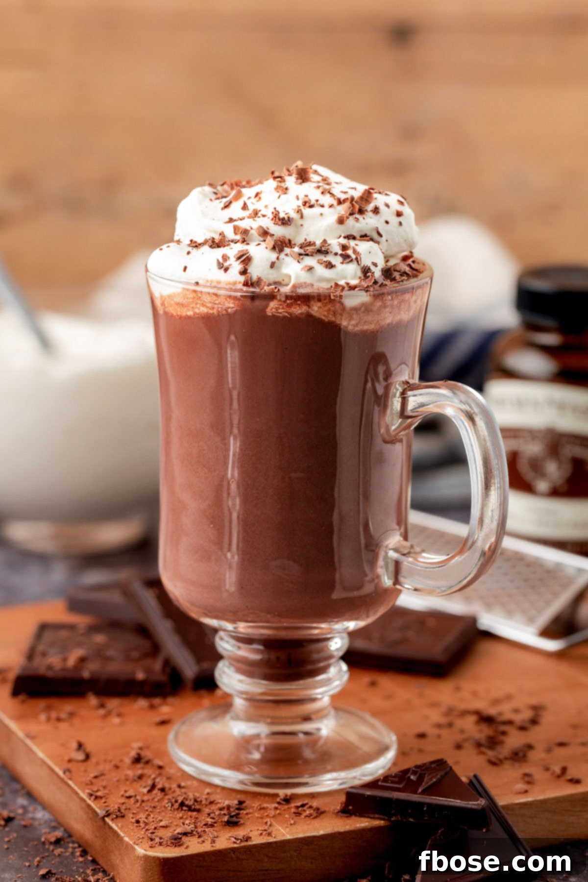 Close-up of a steaming mug of Tini's rich hot chocolate, topped with fluffy peppermint whipped cream and a sprinkle of chocolate shavings.