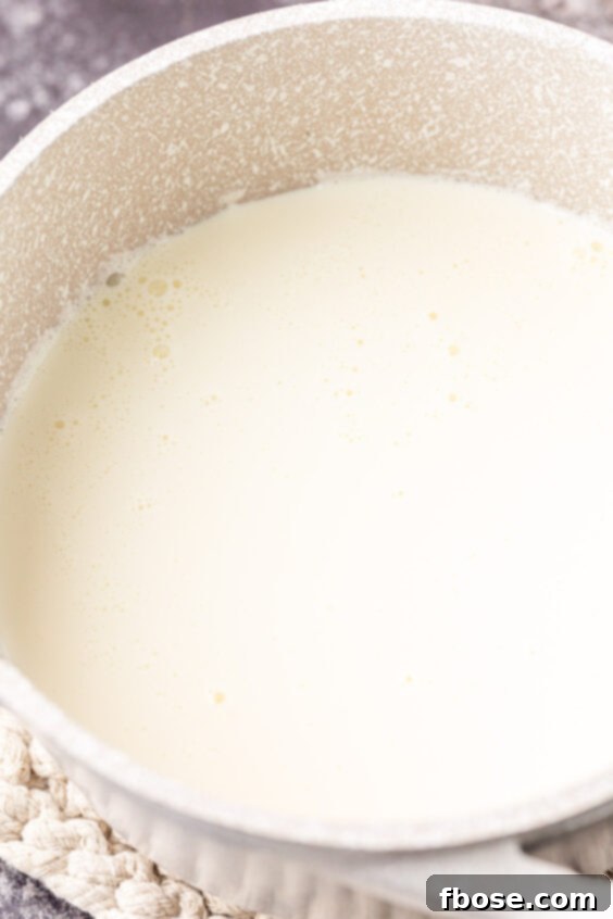 Milk and heavy cream gently heating in a saucepan on the stove.
