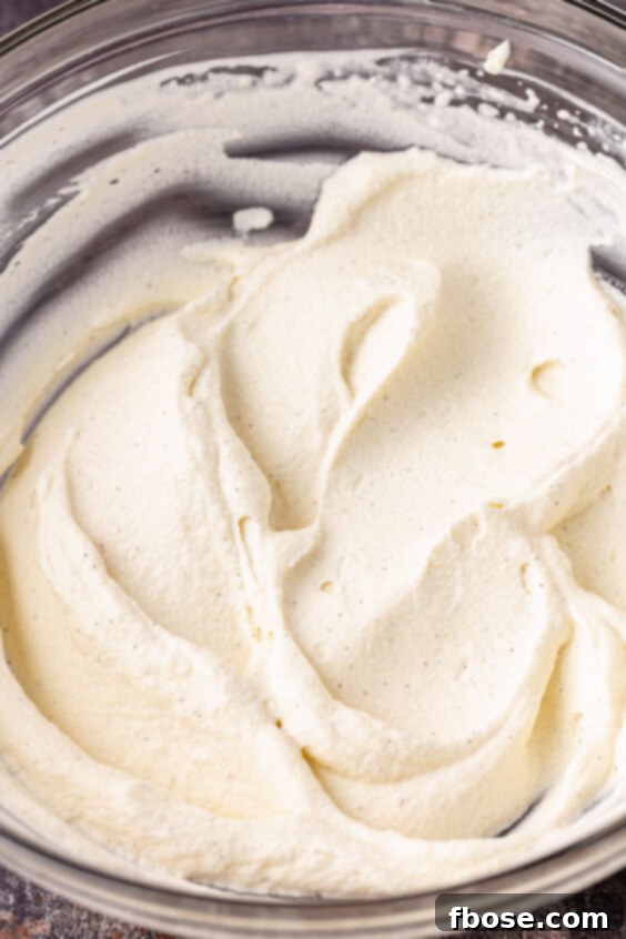 Fluffy peppermint whipped cream prepared in a clear glass mixing bowl, ready for topping.
