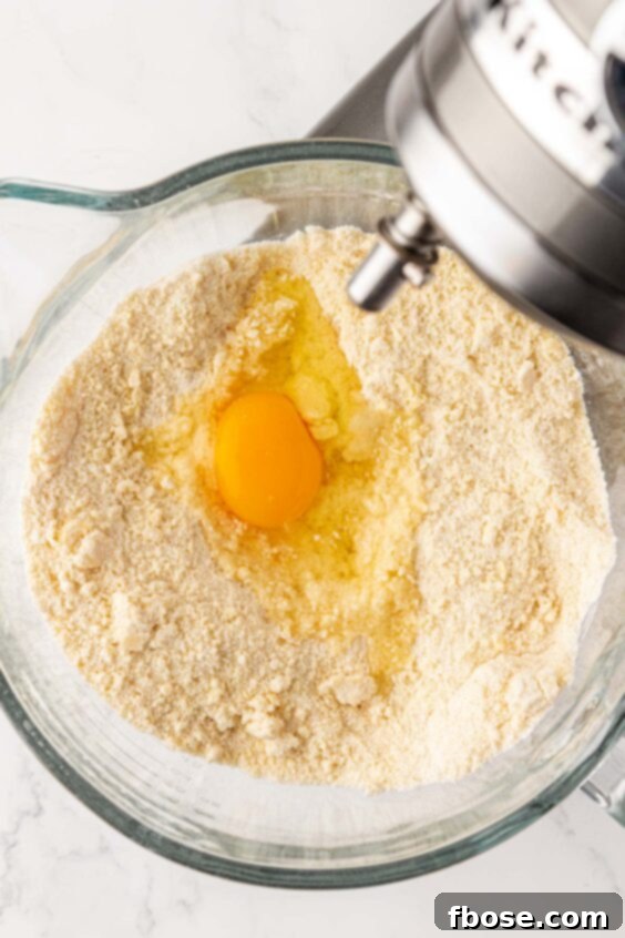 Egg being added to dry ingredients in mixing bowl for cake batter.