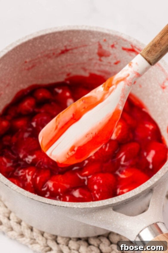 Strawberry filling in a pot with a mixing spatula showing consistency.