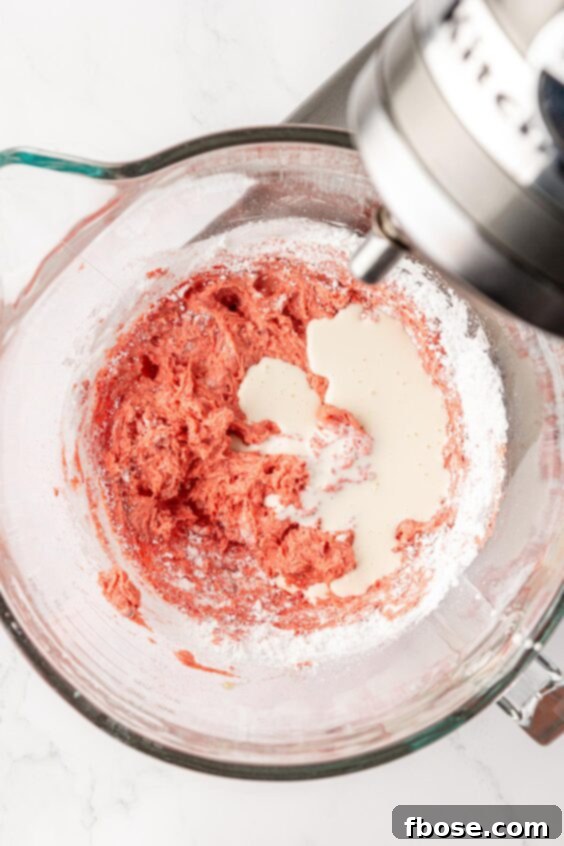 Cream is being added to the strawberry frosting.