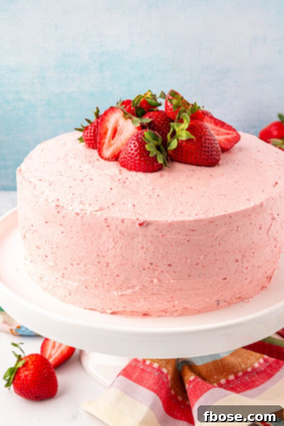 Strawberry cake on a white cake stand.