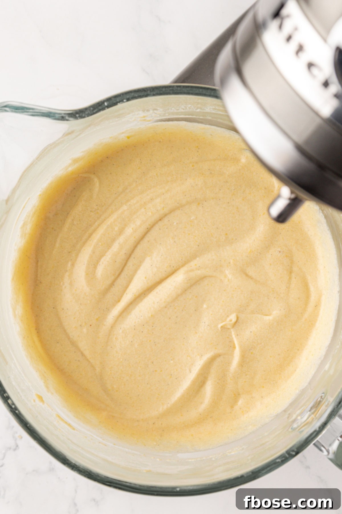 Stand mixer bowl with vanilla cake batter in it.