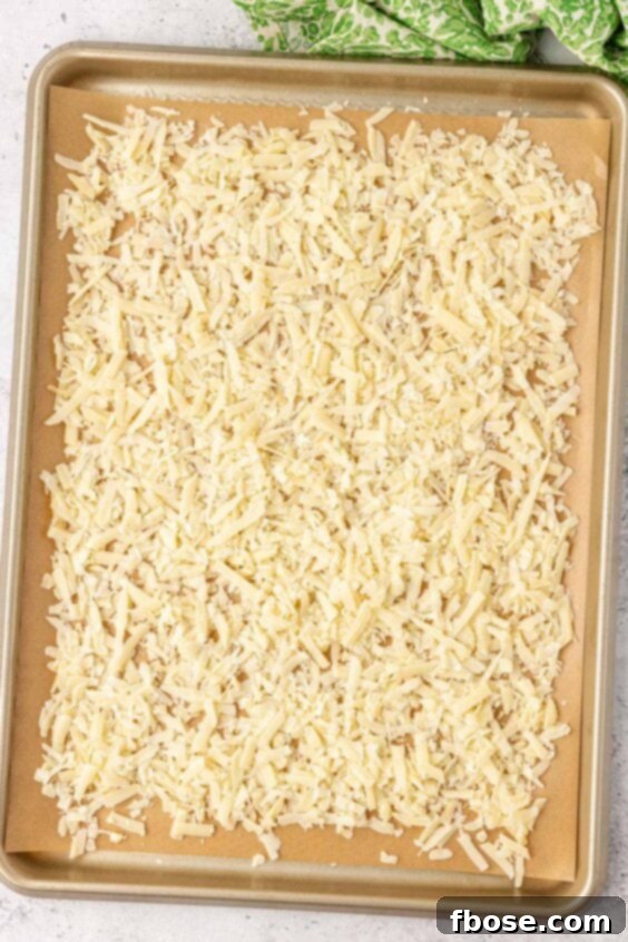 Overhead photo of grated parmesan on a parchment lined baking sheet.