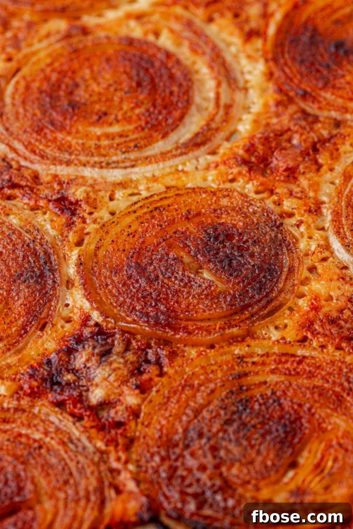 Close-up photo of baked onion ring chips on a parchment-lined pan.