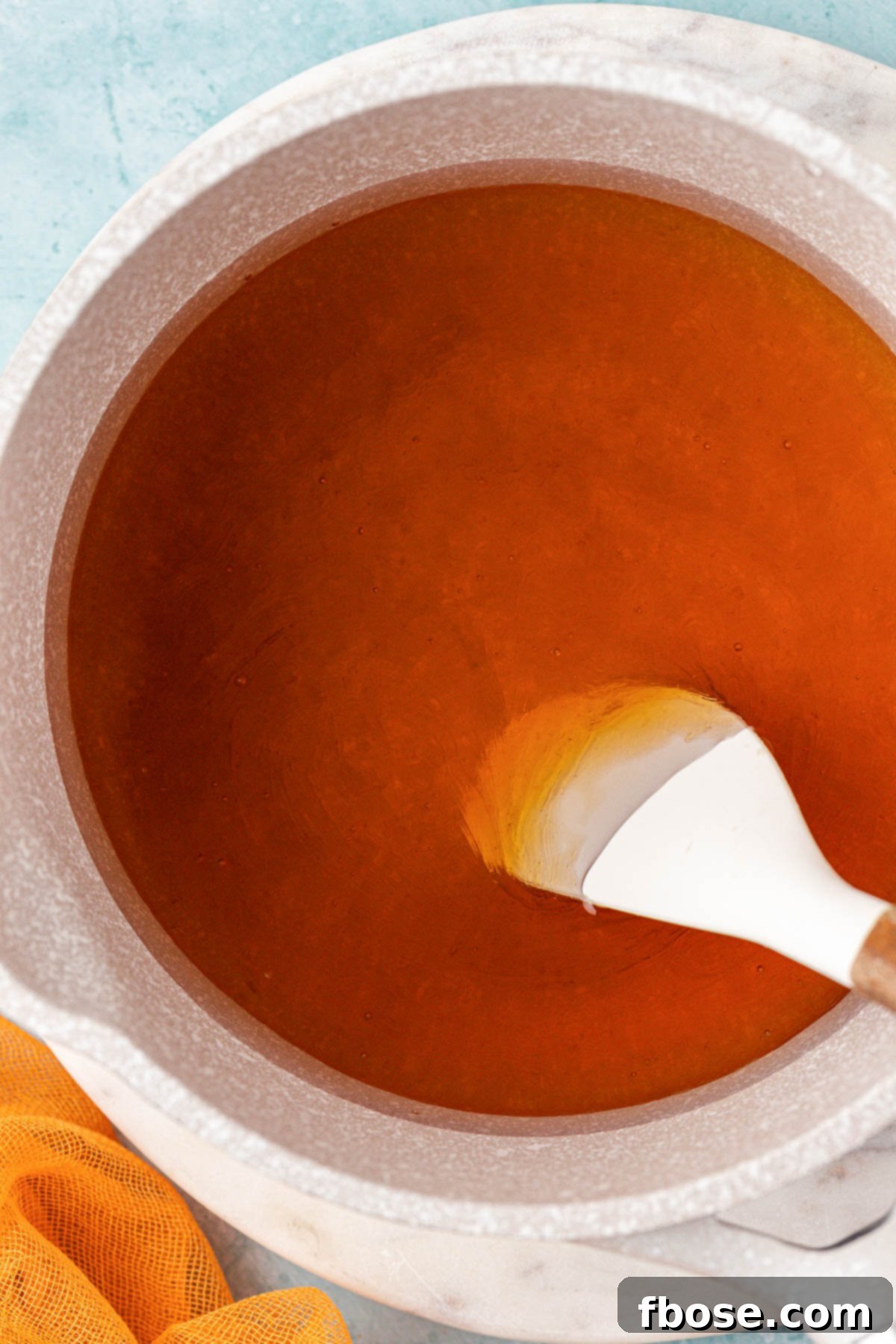 Honey simple syrup being gently prepared in a small pot on a stovetop, illustrating the ease of the process.