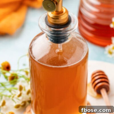 A bottle of honey simple syrup on a table.