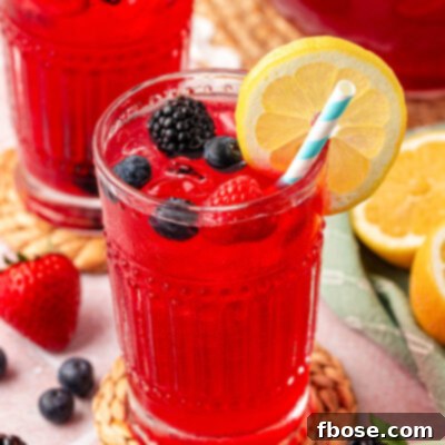 Close up of a glass filled with berry lemonade on a rattan coaster.