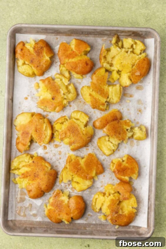 Smashed potatoes on a baking pan ready to be roasted.