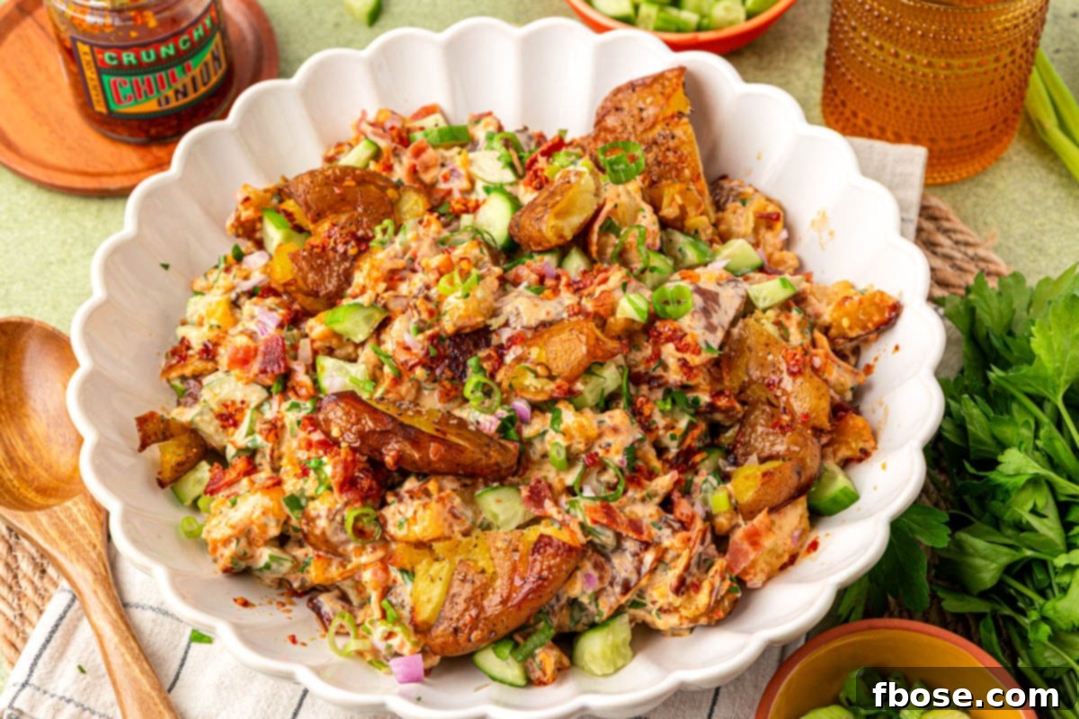 A white scalloped bowl with chili crisp smashed potato salad in it.