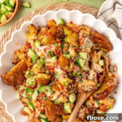 Overhead photo of a white bowl of chili crisp potato salad with a wooden serving spoon in it.
