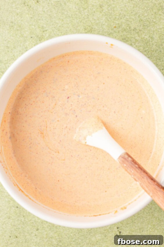Creamy dressing for potato salad being mixed in a white bowl.