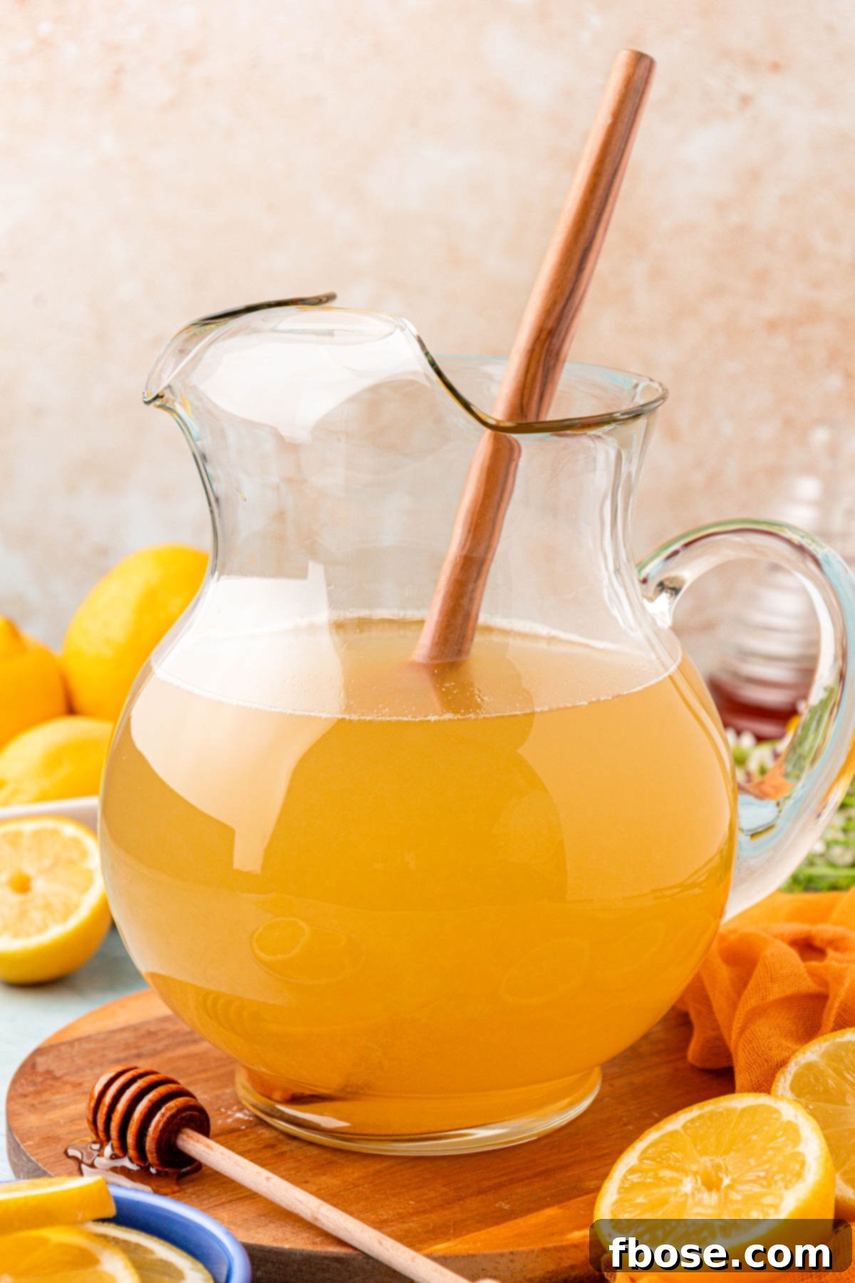 Zesty Honey Delight 5 A glass pitcher with a wooden spoon, ready to mix lemonade with honey.