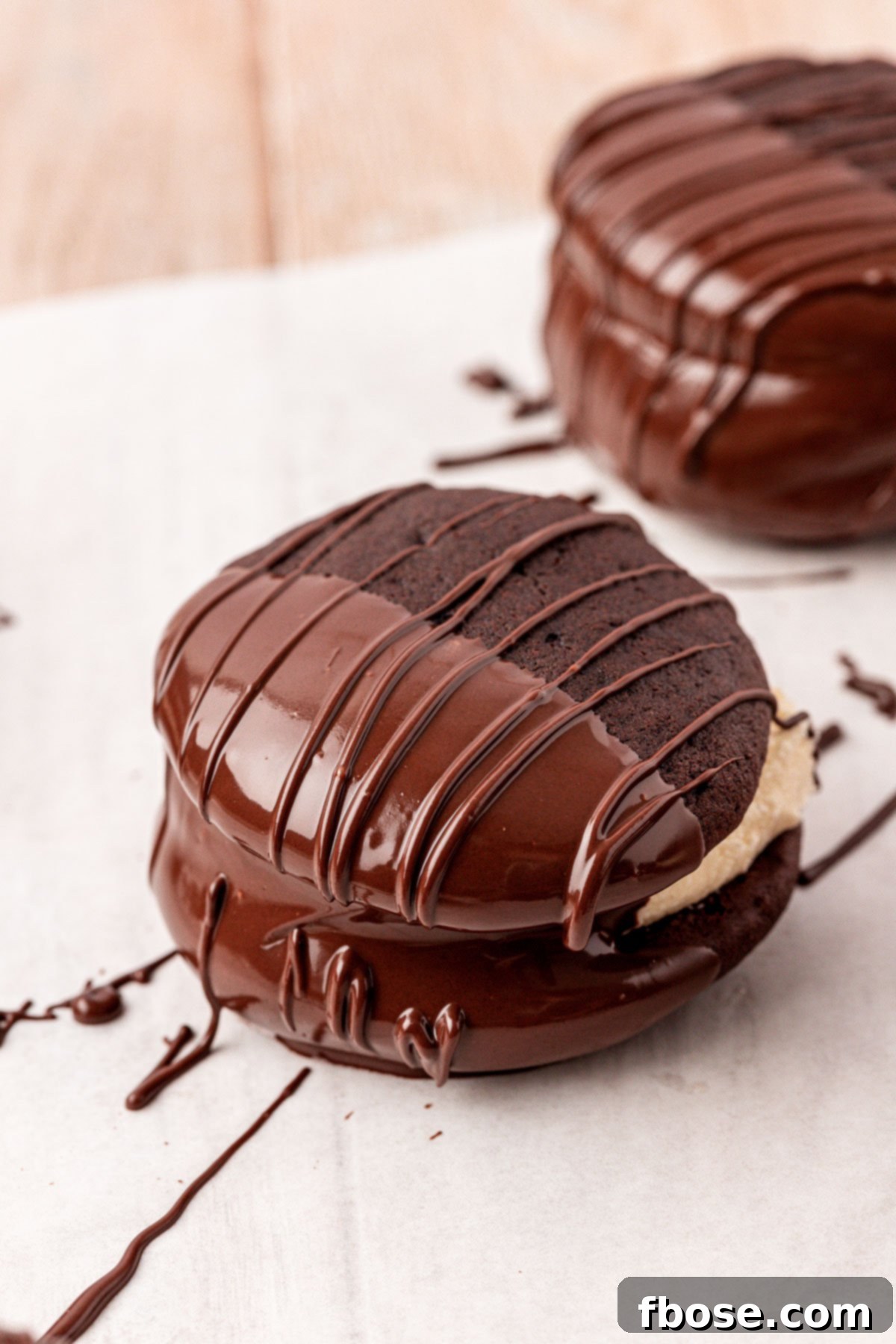 Whoopie pies dipped half way in chocolate on a piece of parchment paper.