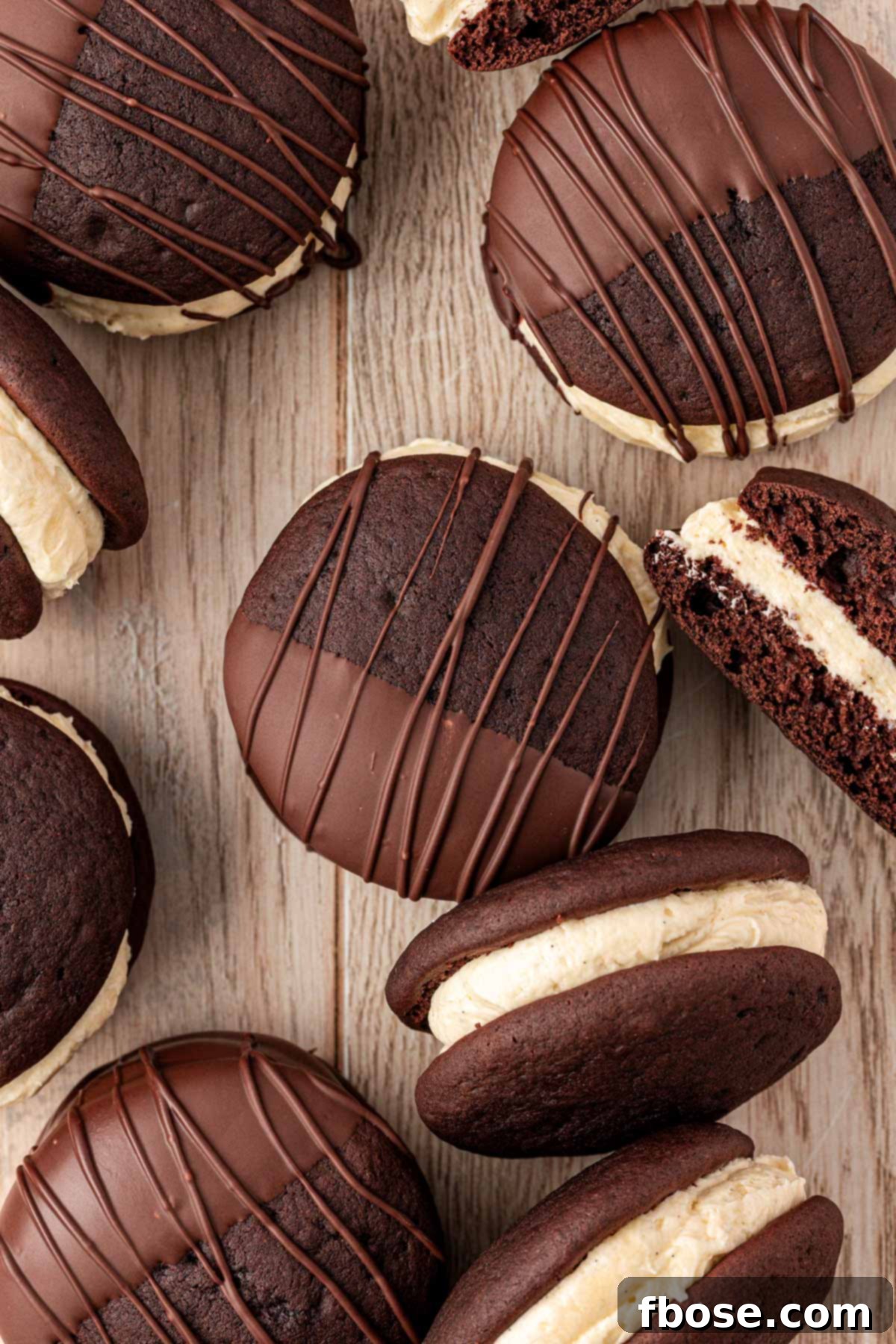 Whoopies pies half dipped in chocolate on a wooden table.