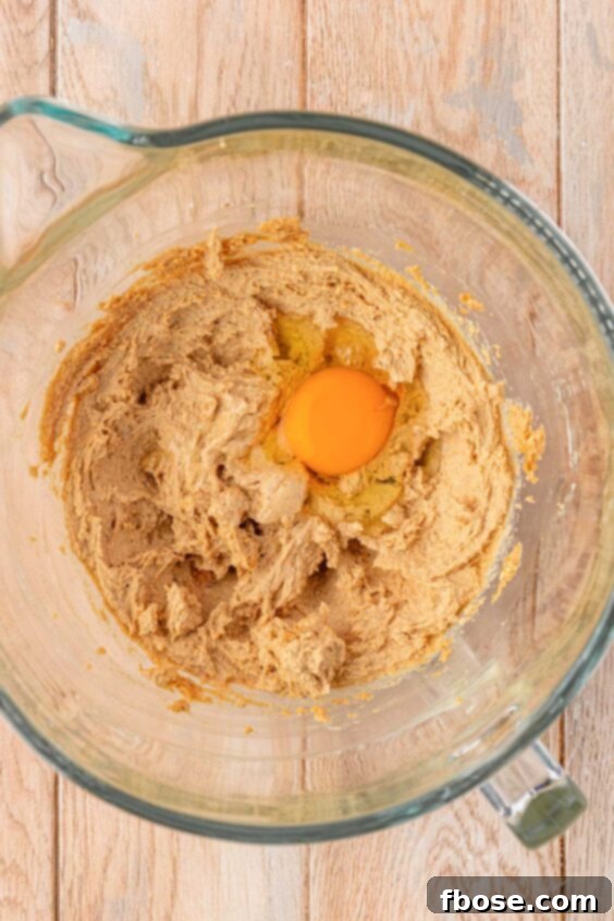 An egg is being added to the batter in a bowl.