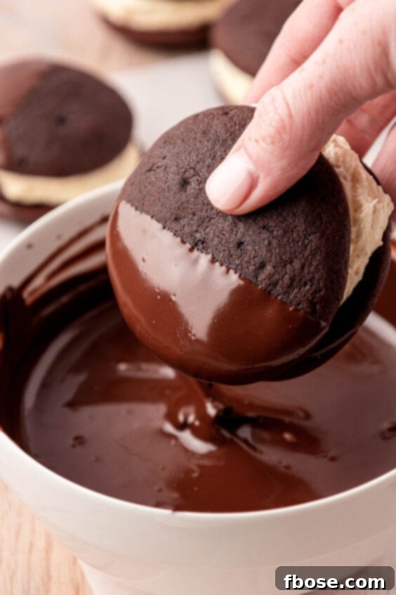 A whoopie pie being dipped into melted chocolate.