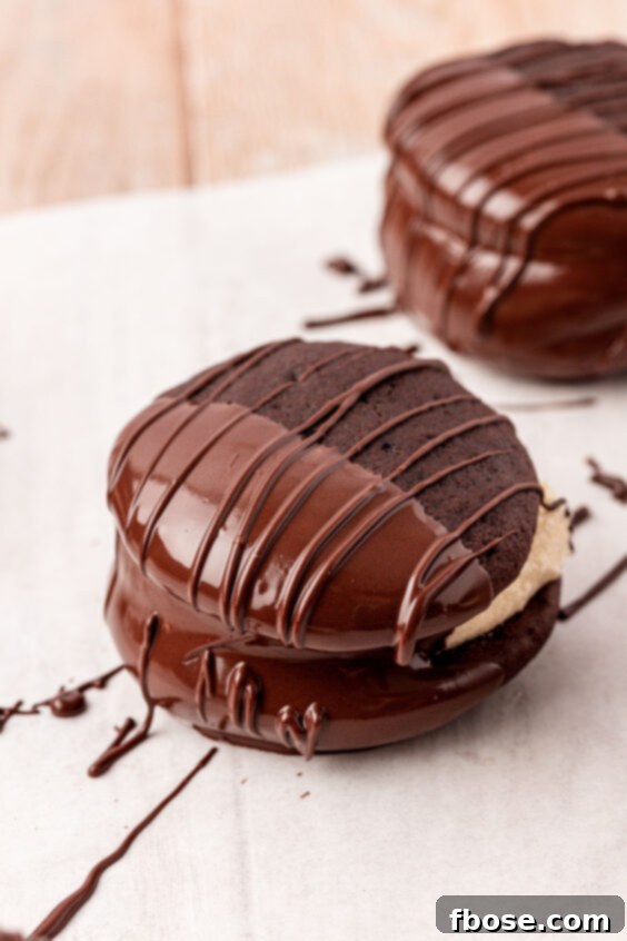Whoopie pies dipped half way in chocolate on a piece of parchment paper.