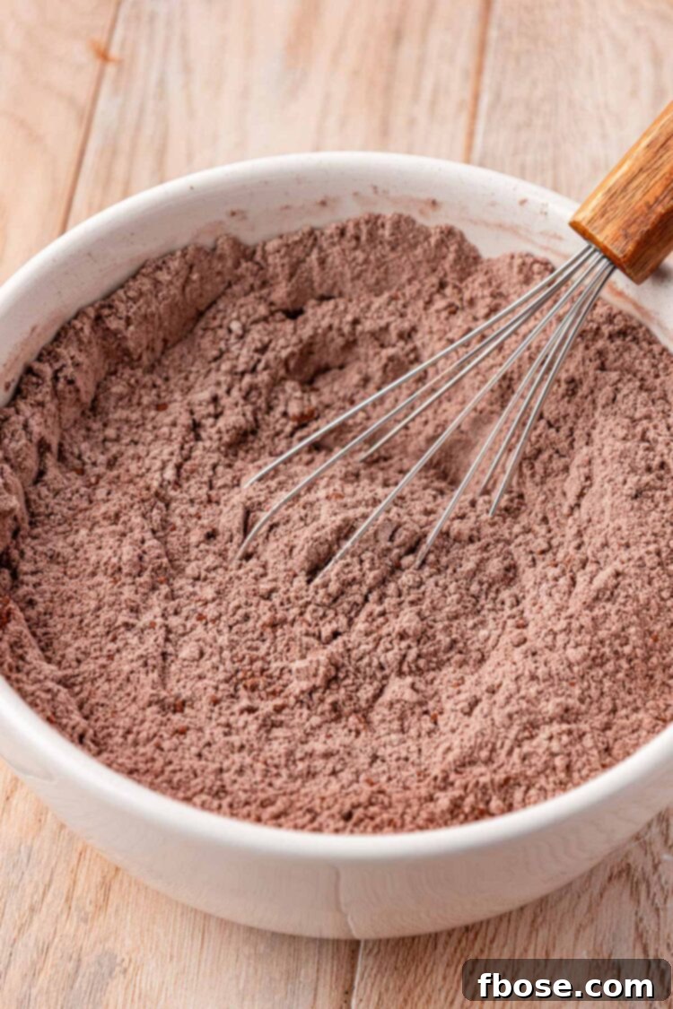 Dry chocolate cake ingredients being whisked in a bowl.