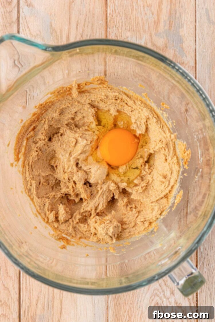 An egg is being added to the batter in a bowl.