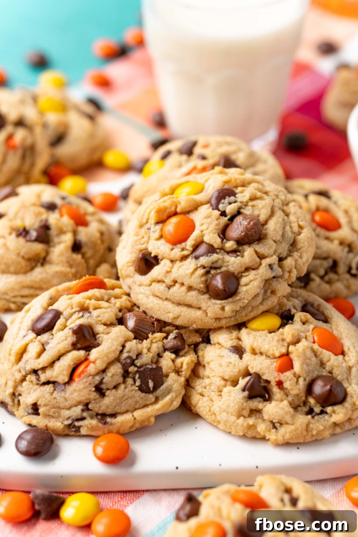 Close up of a peanut butter reese's pieces chocolate chip cookie on more cookies.