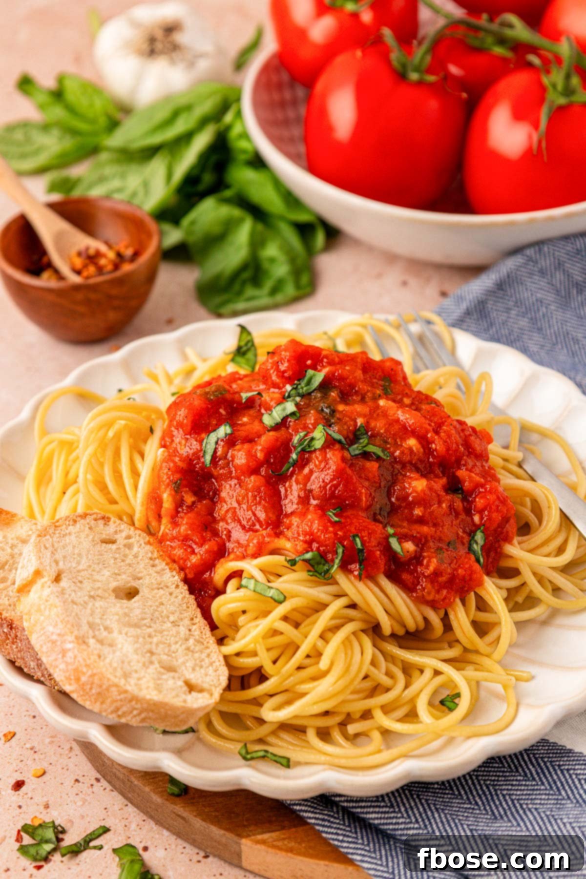 Sun-Kissed Tomato Simplicity 2 A white scalloped plate filled with spaghetti and fresh tomato sauce, and a side of bread.