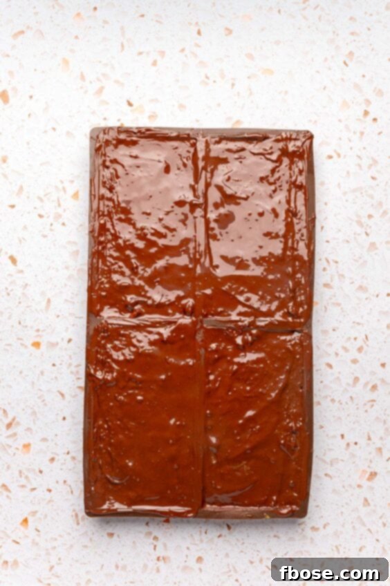 Melted chocolate covering the dubai filling in a candy bar mold, sealing the bar.