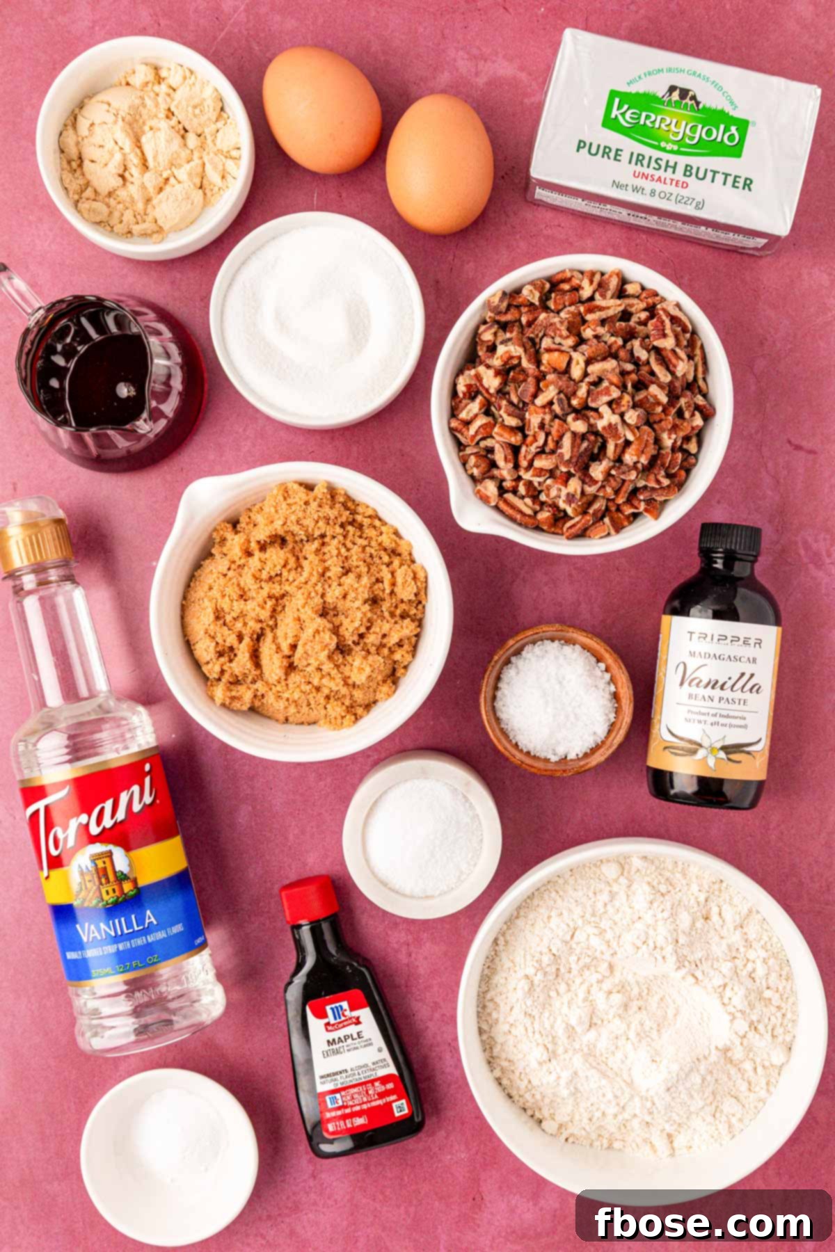 A colorful array of ingredients laid out on a maroon table, ready to be transformed into maple pecan cookies.