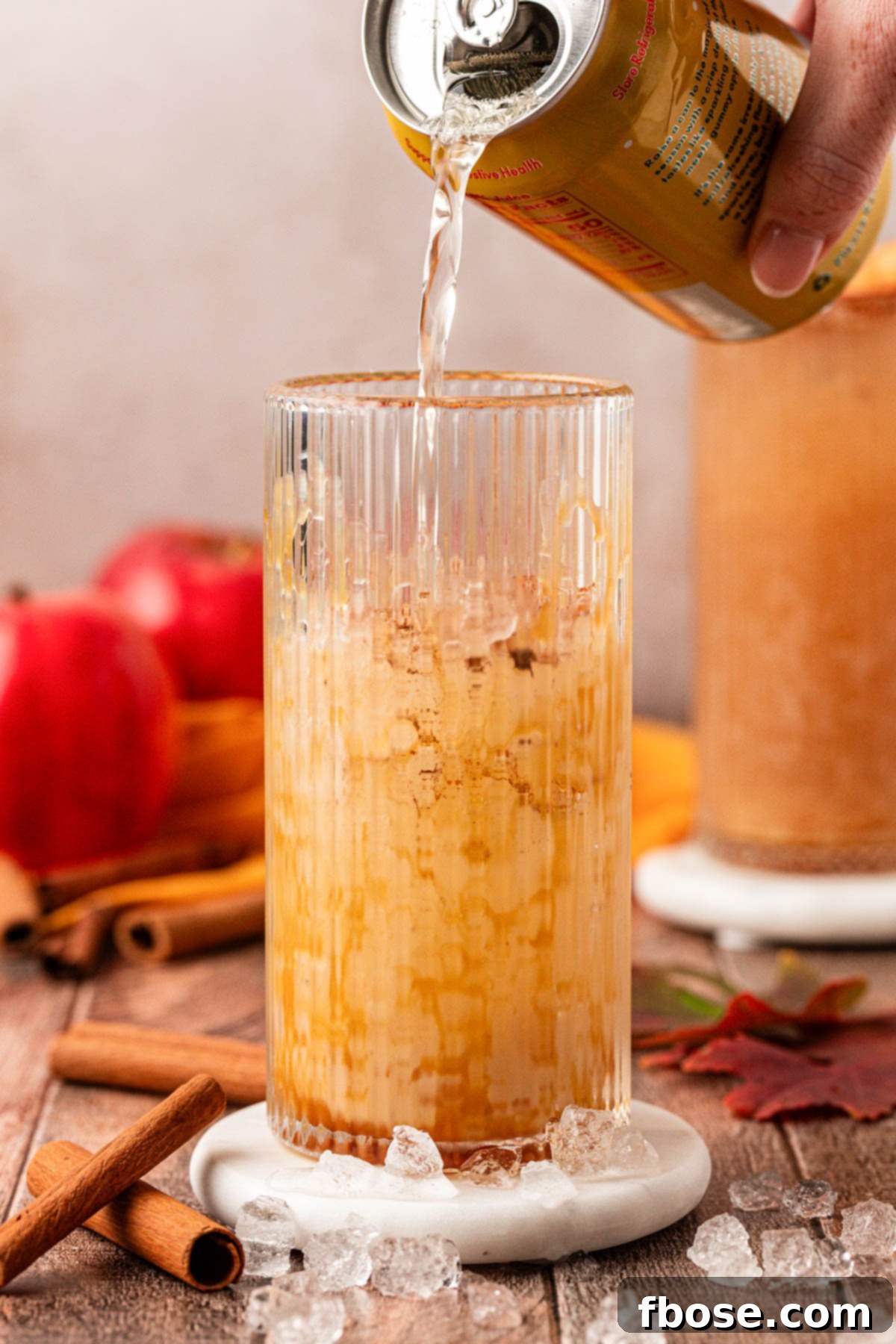 Autumn Crisp Quencher 5 A can of Crisp Apple Olipop being poured into a glass with ice and caramel drizzle.