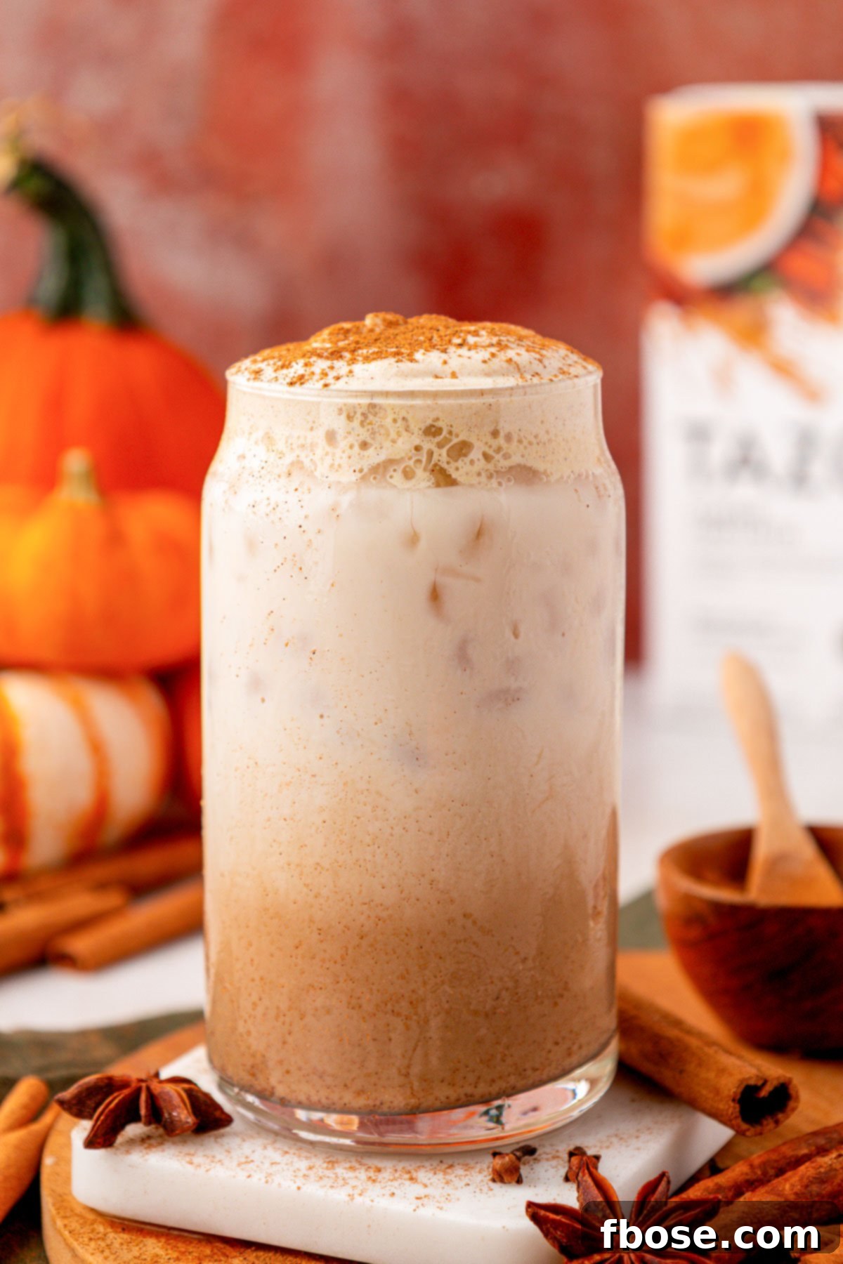 A glass filled with pumpkin cream chai latte on a table.