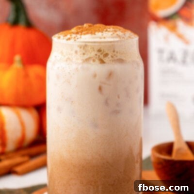 A glass filled with pumpkin cream chai latte on a table.