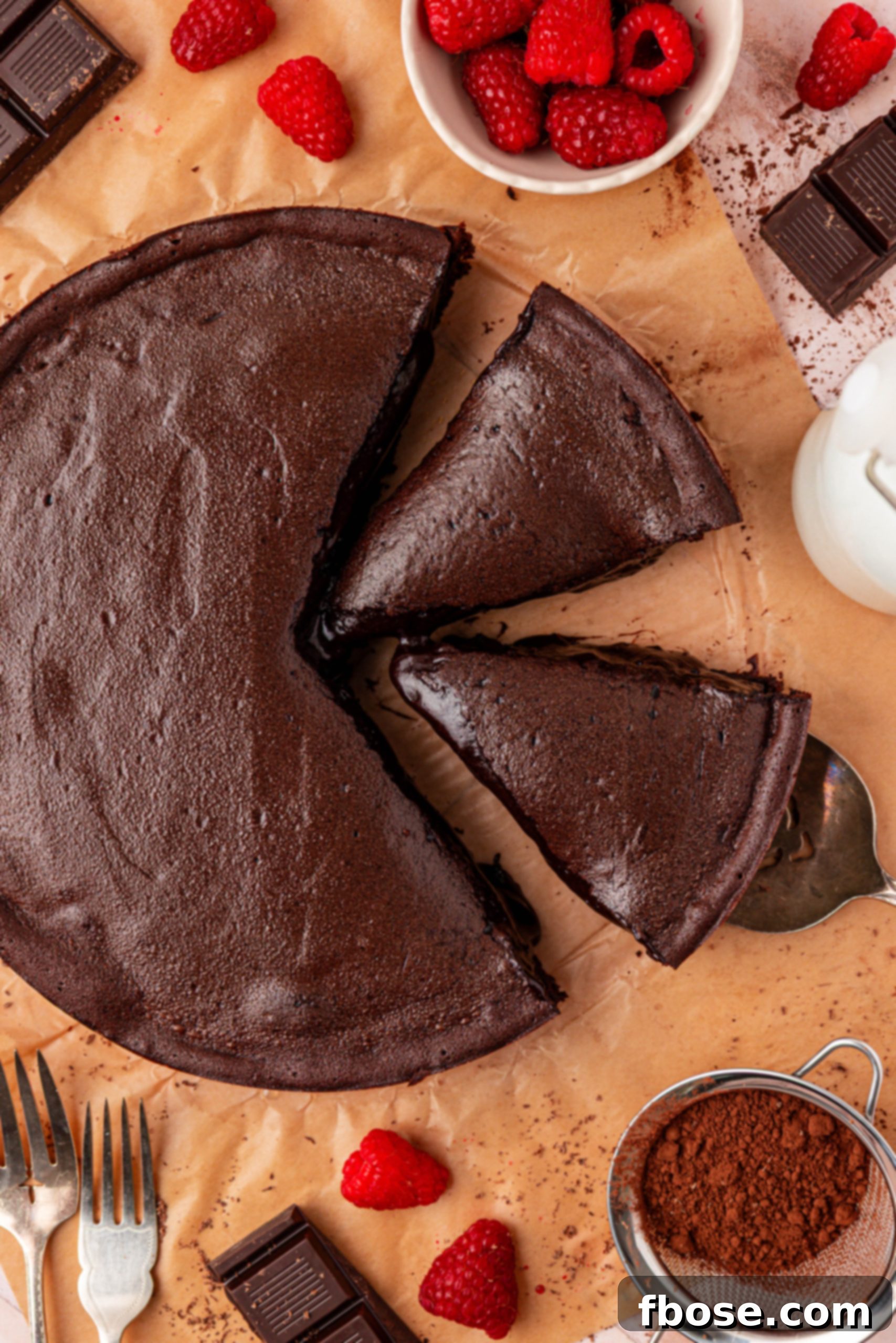 Overhead view of a delectable French Moelleux au Chocolat Cake placed on parchment paper, surrounded by enticing slices.
