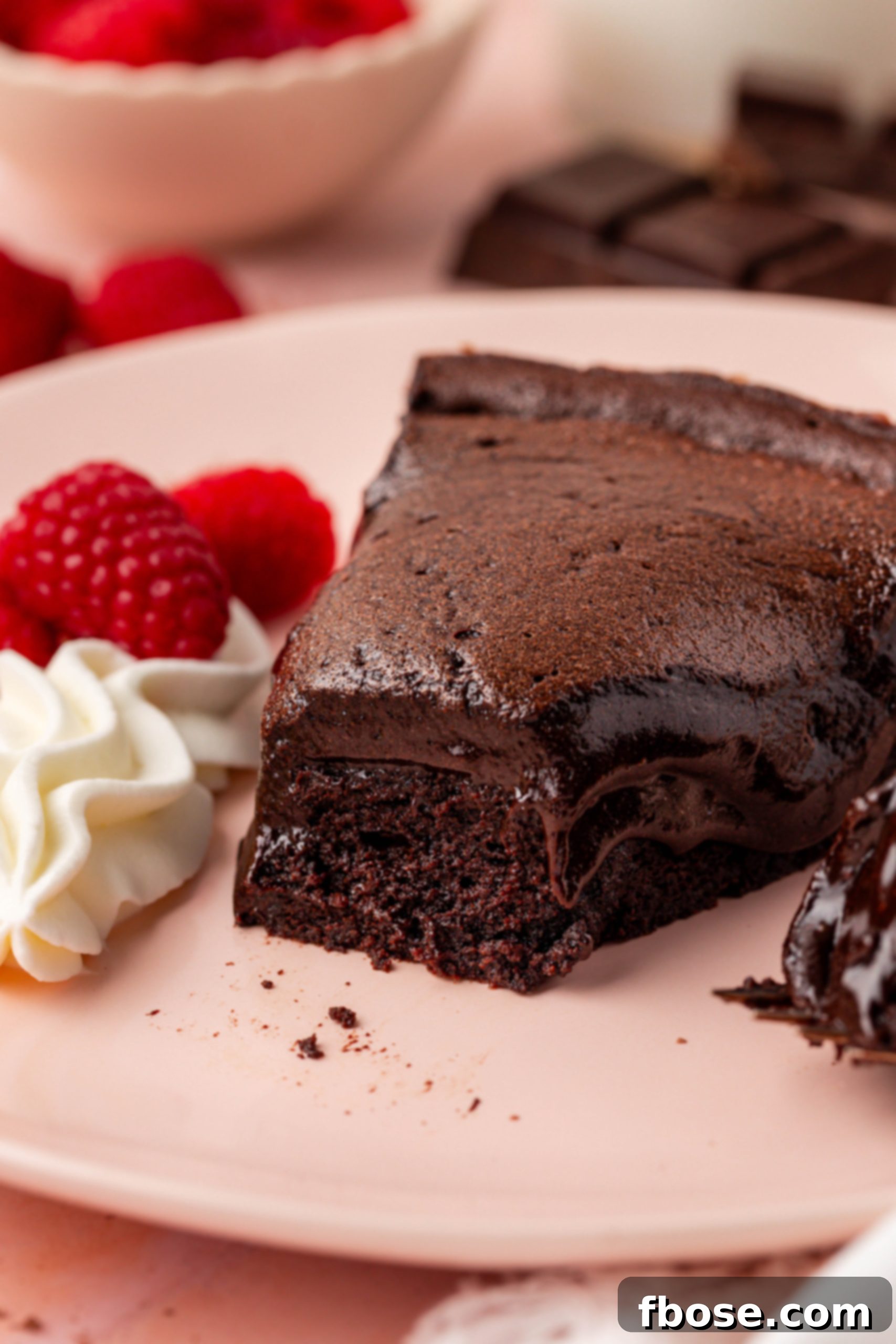 A tantalizing slice of Meolleux au Chocolat cake rests on a pink plate, with a tempting bite already missing.