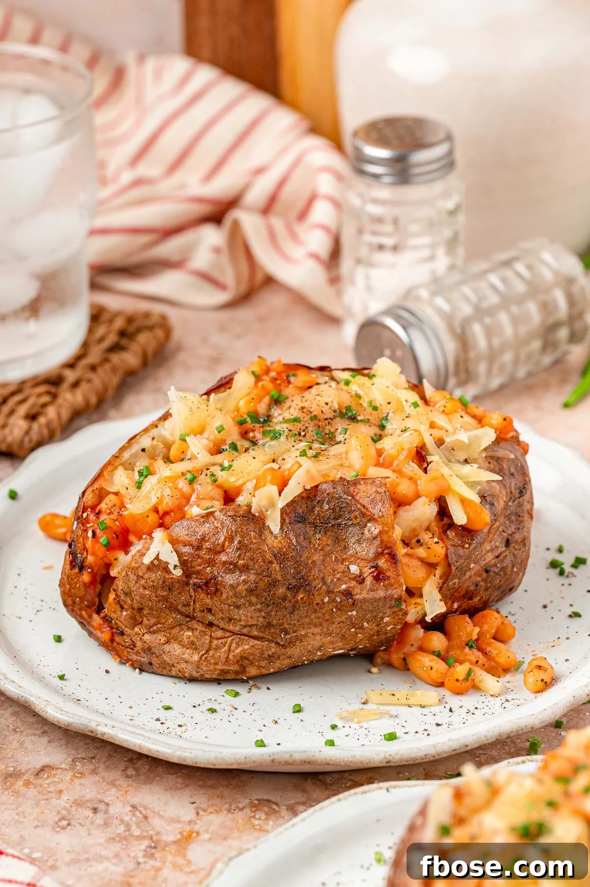 Loaded Jacket Potato with beans and cheese on a white plate.