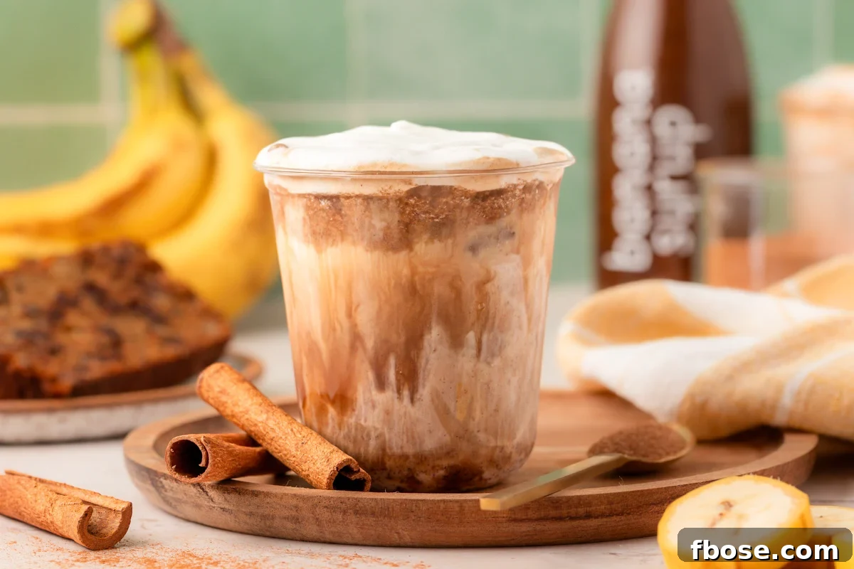 A cup with banana bread latte on a wooden tray.