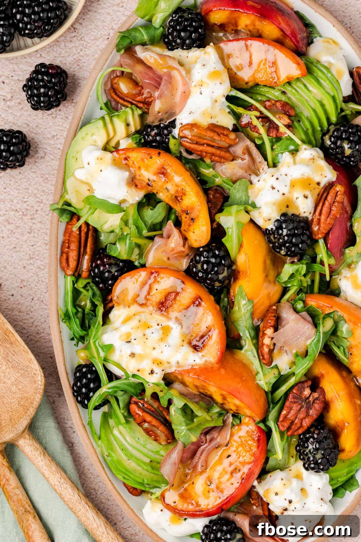 Close up of a burrata and peach salad on a plate.