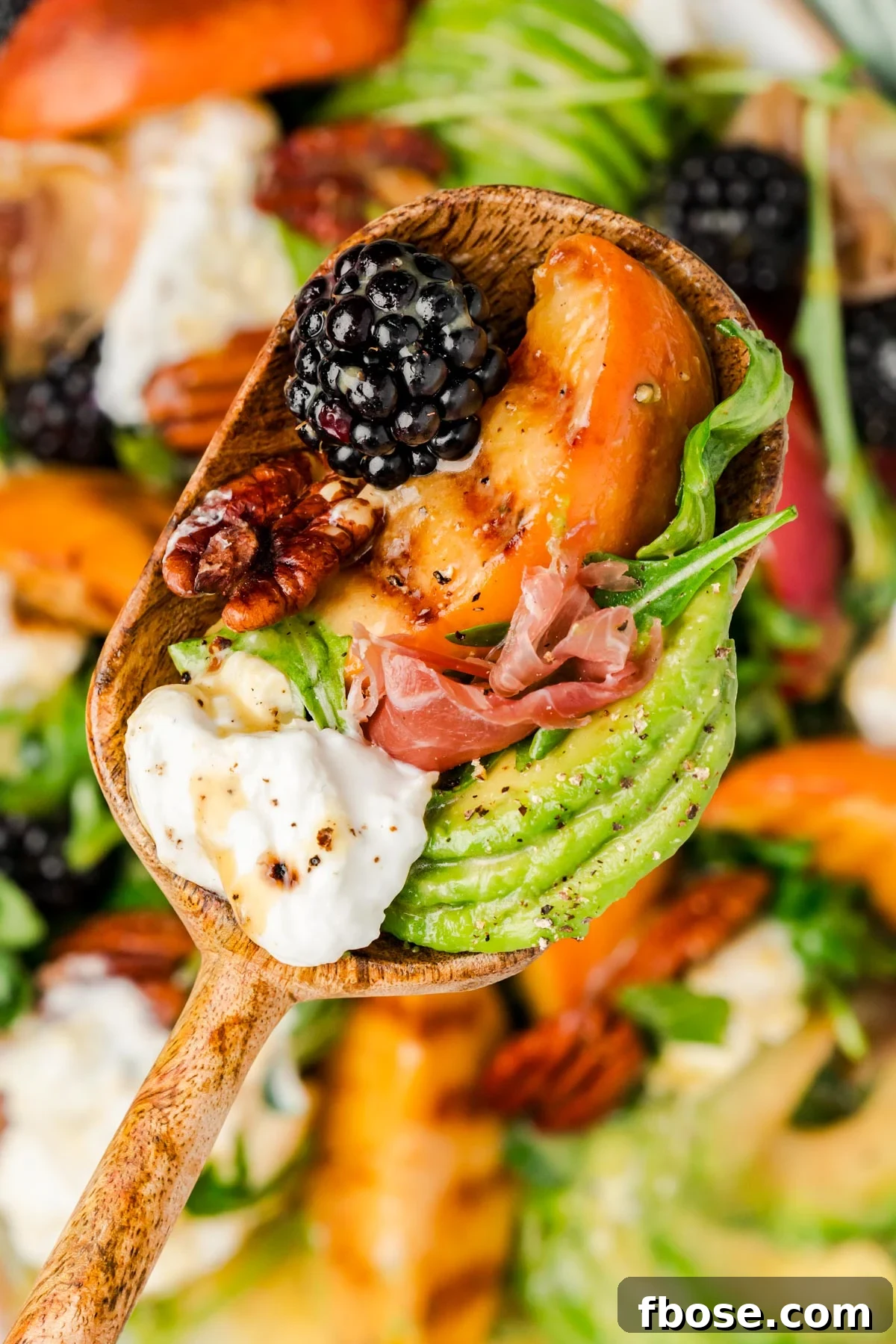 A serving spoon of burrata peach salad.