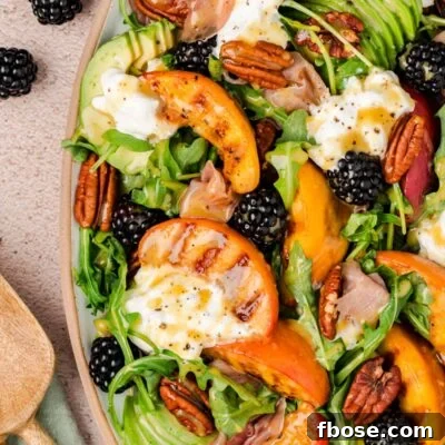 Close up of a burrata and peach salad on a plate.