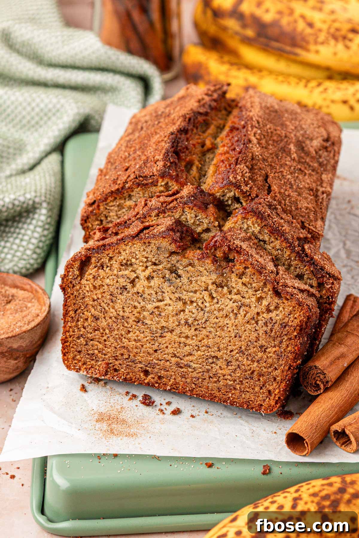 Brown Butter Banana Bread Recipe 2 A loaf of banana bread with browned butter on a piece of parchment paper, some of it has been sliced.
