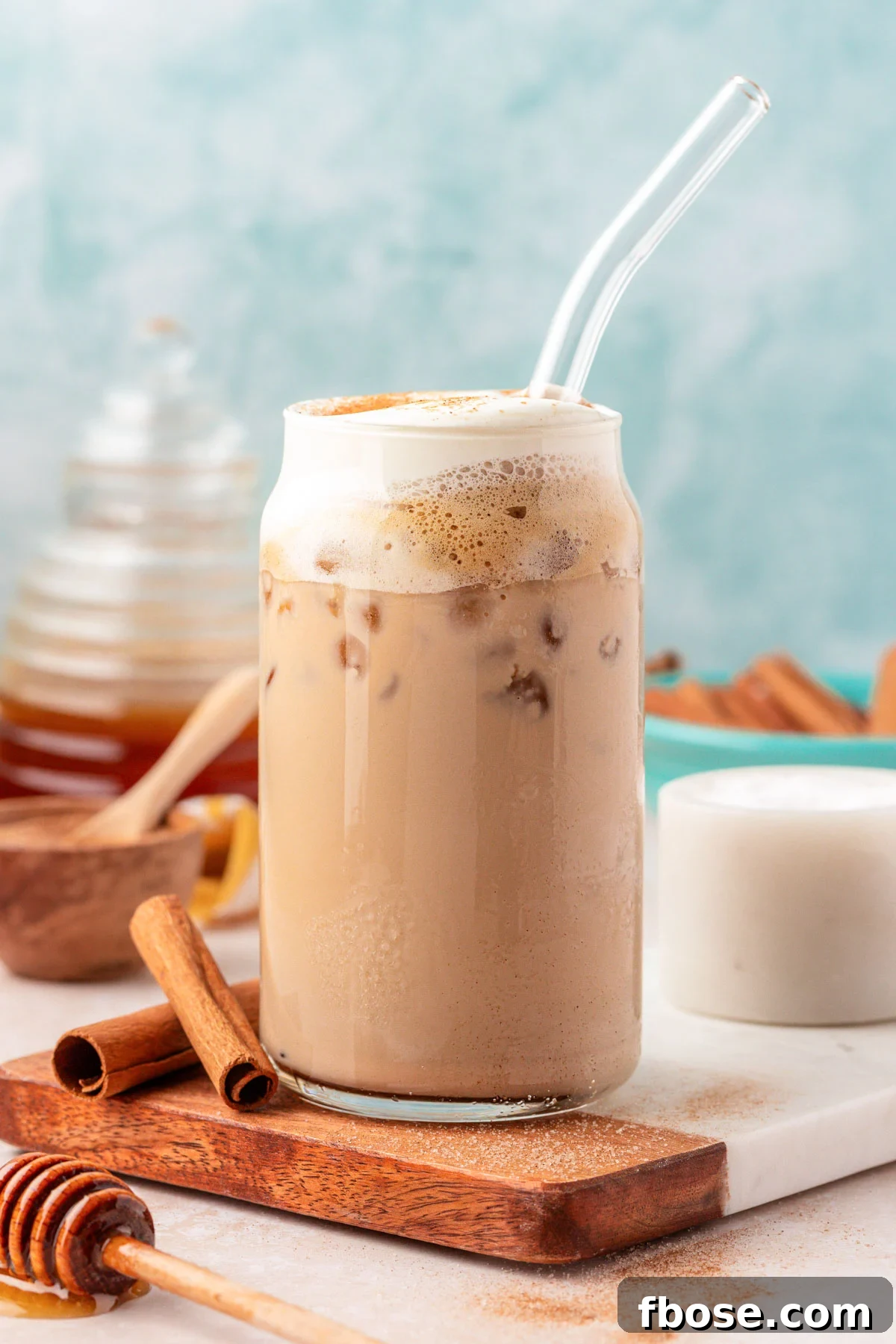 Close up of an iced salted honey latte in a glass with a straw.